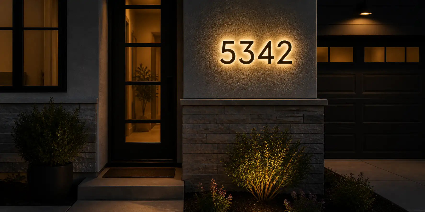 Custom solar LED house number 5342 glowing with warm white light on a modern exterior wall at night